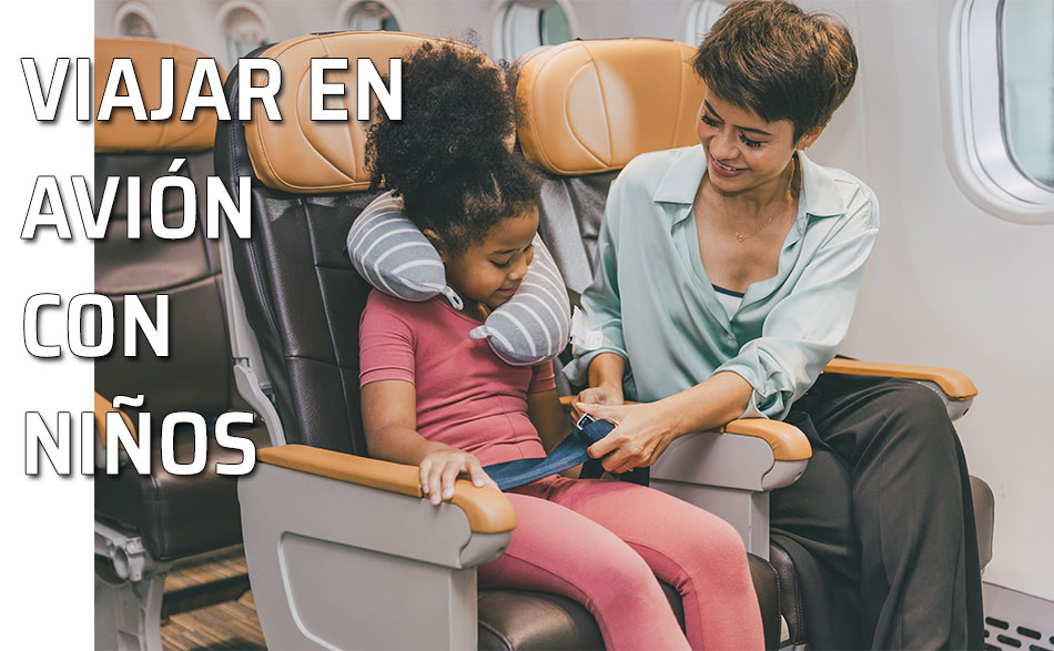Una madre pone el cinturón de seguridad a su hija en el asiento de un avión