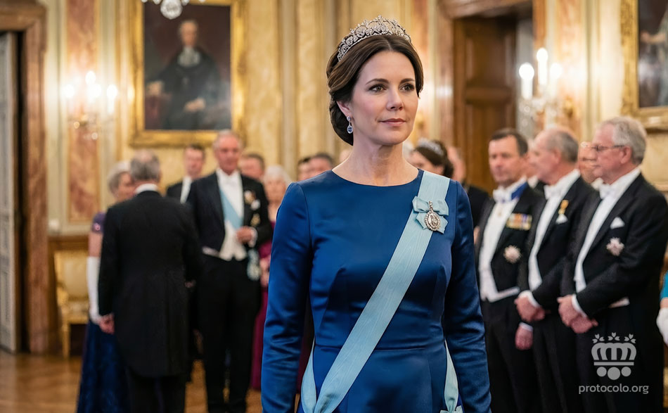 Las mujeres visten la banda por encima del vestido. En el caso de las mujeres pueden llevar una condecoración en la misma banda o en el lazo