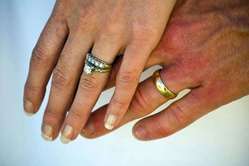 Manos con las alianzas de casado y anillo de compromiso.