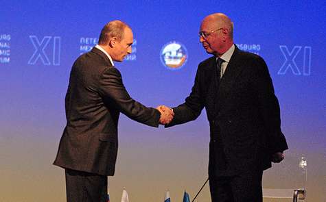 Vladimir Putin y Klaus Schwab se dan la mano.